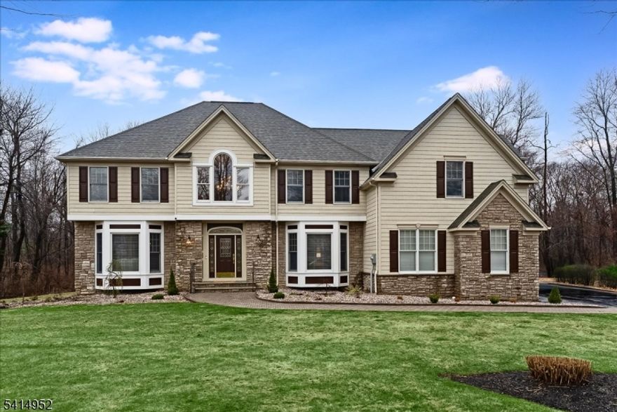 Premier Colonial on a coveted cul-de-sac in the highly desirable Stone Rows neighborhood. This impressive home welcomes you with a grand foyer and immediately showcases timeless style, warmth, and thoughtful design. The main level offers a formal living room and elegant dining room perfect for entertaining. Rich wood flooring flows throughout the primary living areas, adding warmth and character.The heart of the home is the dramatic two-story family room featuring soaring ceilings, a wood-burning fireplace, and walls of windows that flood the space with natural light. The sun-filled kitchen is designed for both everyday living and entertaining, offering a center island, granite countertops, wine refrigerator, abundant cabinetry, generous workspace, and a bright breakfast area.Step outside to the mahogany deck overlooking the backyard, ideal for relaxing or gathering with guests. A mudroom with garage access, a flexible office or den, and a convenient powder room complete the first floor.Upstairs, the luxurious primary suite offers walk-in closets, a private sitting area, and a spacious bath with a jetted soaking tub and stall shower. Three additional bedrooms, two full baths, and second-floor laundry add convenience.The partially finished basement provides versatile space for recreation, fitness, or media. Close to major roadways and all Sparta Township amenities.