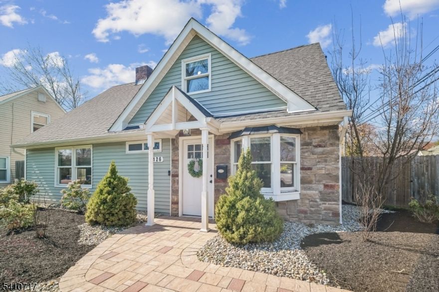 Fabulously renovated, this four-bedroom, three-full-bath Cape Cod offers an appealing blend of style, comfort, and flexibility, complete with an oversized detached garage and storage loft. A paver walkway, covered front entrance, and stone-accented facade create inviting curb appeal. Inside, the open floor plan offers versatile living and entertaining spaces. The sun-filled living room with bay window flows seamlessly into the dining area with chandelier. The modern kitchen features white cabinetry, calacatta quartz countertops, stainless steel appliances, and a deep blue center island with seating and pendant lighting, while open sightlines to the family room help keep daily living and entertaining connected. The family room offers a comfortable gathering space with a stone fireplace and sliding doors to the paver patio. A spacious first-floor bedroom is well suited for guests, with a nearby full bath featuring a walk-in glass shower. Luxury vinyl flooring, recessed lighting, and a convenient laundry closet with pantry storage complete the first level. Upstairs, the bright primary suite includes a walk-in closet and full bath with custom tiled shower and vanity, both enhanced by barn-style doors. Two additional bedrooms share a hall bath. Outside, recently updated landscaping in the front and back yards includes perennial plantings, while a wood-fenced private rear yard offers garden areas, a paver patio for outdoor dining, and open lawn space for recreation.