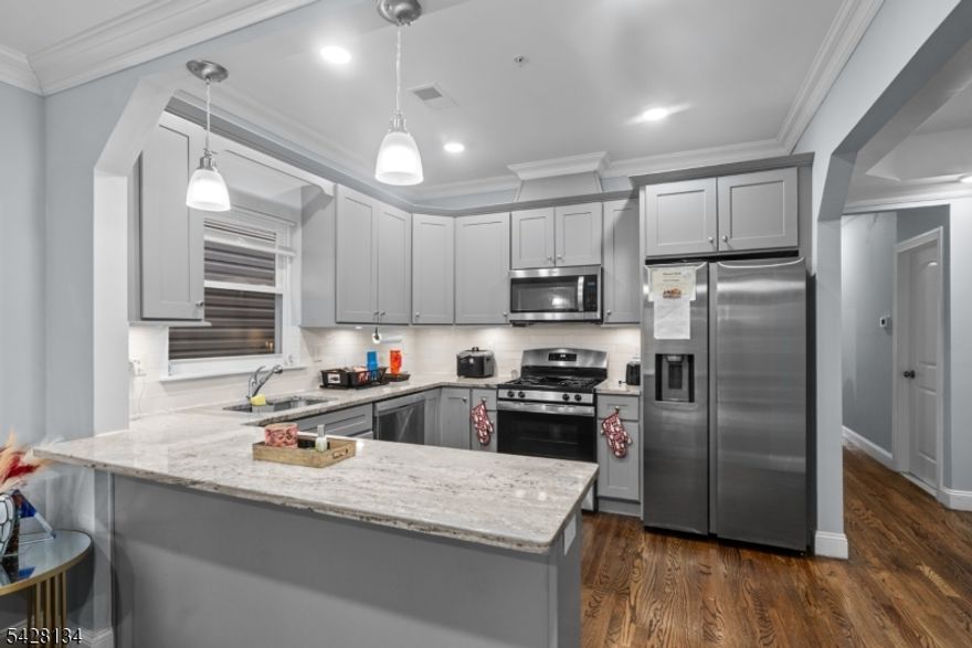 Newer construction two-family home offering modern design and excellent income potential. Each unit features 3 spacious bedrooms and 2 full bathrooms with open-concept layouts, hardwood floors, and abundant natural light throughout. The kitchens are equipped with stainless steel appliances, a breakfast bar on the 2nd and 3rd floors, and flow seamlessly into a separate dining room, perfect for everyday living and entertaining. Primary suites include walk-in closets and private en-suite bathrooms, while each unit also offers its own laundry for added convenience. Sliding glass doors on the ground floor provide direct access to a private, vinyl-fenced backyard, ideal for outdoor enjoyment. Additional highlights include balconies on both the 2nd and 3rd floors, a bonus 1-bedroom, 1-bath unit for extended living or added rental income, and a 2-car garage for off-street parking. Conveniently located on a quiet residential street just 10 minutes from Newark Penn Station, you'll enjoy an easy commute to NYC or Hoboken. Surrounded by local parks, delis, shops, and restaurants, with convenient access to bus, rail, and other transportation options this is a city living with a neighborhood feel!