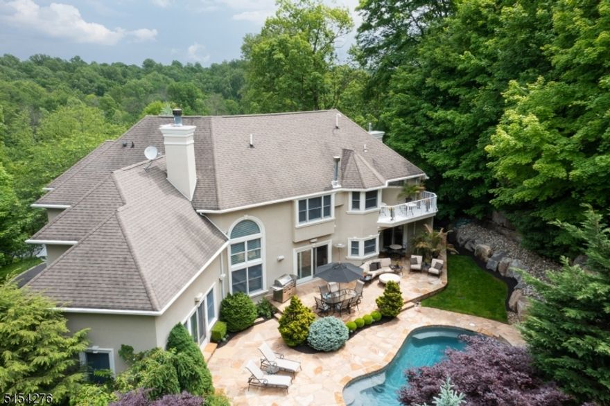 Immaculately maintained and updated custom home, with thoughtful finishes and amenities throughout. Located on a quiet cul de sac, and set high above the street with manicured, mature landscaping. Fully-drainable, real hardcoat stucco exterior. Open floor plan and tall windows invite natural light. Today's colors/styles/decor flow seamlessly throughout this truly move-in ready home complete with whole-home audio system. An entertainer's dream with a kitchen featuring professional appliances & custom wine storage, dining room with see-through gas fireplace and French doors, and a purpose-built billiard room/bar that all open directly to the resort-like backyard. Central to the outdoor entertainment enclave is the newly resurfaced, custom pool with spa and waterfall, set into the natural topography of the land. Pool and gardens are encased by tall trees creating a very private Shangri-La, just steps from the kitchen and bar. The main level also features a bespoke cherry study, sunken family room with wood-burning fireplace, and an en-suite guest bedroom. Dual staircases lead to the upper level which boasts a master suite with vaulted ceilings, a gas-burning fireplace, jetted tub, radiant heat floor, oversize dual-head shower, large walk-in closet, and a balcony which overlooks the backyard oasis, and 2 additional BRs with a jack and jill bath. The lower level features a 5th BR and full bath. The home is protected by a monitored security system and a whole-home generator.