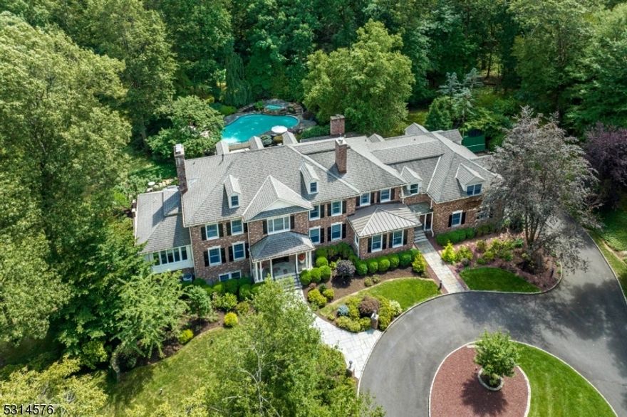Nestled at the end of a private lane, this magnificent 17-room brick estate offers unparalleled privacy and timeless elegance. A sweeping driveway leads to a grand 7.9-acre property featuring a stunning pool with spa, surrounded by multiple terraces, patios, and a spacious green lawn ideal for outdoor entertaining or quiet relaxation. Inside, the home boasts three full floors of meticulously crafted living space, showcasing high-end finishes throughout. The flexible floor plan easily accommodates both intimate gatherings and lavish entertaining. The estate includes 5 generously sized bedrooms, multiple office spaces, a handsome library, sun-filled solarium, wine cellar, exercise area, recreation room with a wet bar, and gracious living and dining rooms. The gourmet kitchen is a chef's delight with its full size SubZero refrigerator and freezer, six-burner dual fuel Wolf range with double ovens and a griddle, two-burner electric Gaggenau cooktop, massive center island topped with granite, two Bosch dishwashers, separate dine-in area and pantry. With 5 fireplaces, hardwood floors, and soaring 10-ft ceilings on the first floor (9-ft on the second), every room feels warm, inviting, and filled with natural light.  This exceptional property located onthe east-side of Mendham offers serene, luxurious living with ample space for both relaxation and productivity truly an extraordinary place to call home.