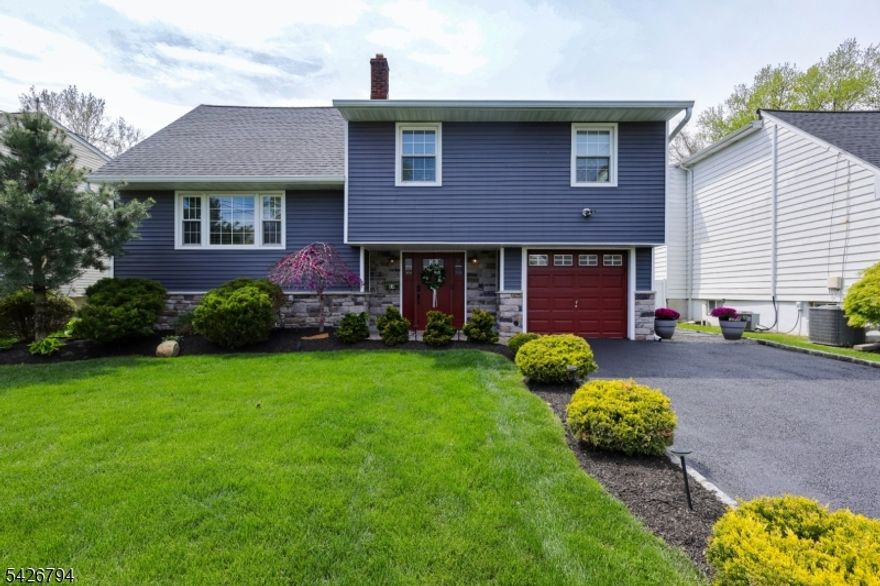 A true standout, this impeccably renovated split-level residence offers turnkey living on a quiet, tree-lined street in one of the area's most sought-after neighborhoods just moments from downtown, premier shopping, top-rated schools, parks, and direct NYC transportation.Thoughtfully designed with both style and functionality in mind, this 4-bedroom, 2.5-bath home features a seamless, open-concept layout ideal for modern living and effortless entertaining. Sunlit living and dining spaces flow into a beautifully appointed kitchen, complete with direct access to an expansive Trex deck for elevated indoor-outdoor living. The large back patio is perfect for entertaining. The home's versatile lower level offers a fully finished basement perfect as a sophisticated lounge, media room, or private retreat alongside generous storage. A well-placed laundry room with powder room enhances everyday convenience. Upstairs, spacious bedrooms provide comfort and privacy, highlighted by a serene primary suite featuring a walk-in closet and a spa-inspired en-suite bath. Set on an exceptional 60 x 160 lot one of the largest in town the property backs to scenic trails, offering a rare sense of privacy and natural beauty. A full-house generator adds an additional level of comfort and security. House also comes with EV charger.