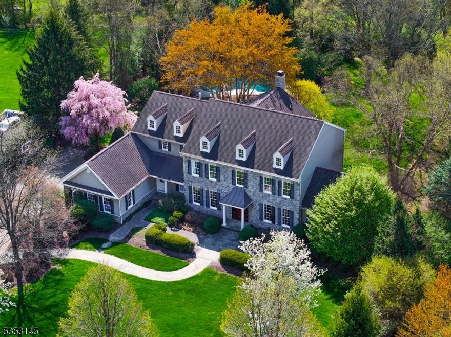 Experience timeless elegance in this exceptional 4-bedroom, 5.1-bath center hall colonial, nestled on 1.28 private acres in the coveted Canterbury Estates of Basking Ridge. Surrounded by mature trees and manicured lawns, this home offers a true neighborhood setting with sidewalks, bike paths, and natural beauty. The grand two-story foyer with oak staircase introduces refined interiors. The family room features 10-foot ceilings and a soaring stone fireplace, while formal living and dining rooms provide an elegant backdrop for entertaining. The sun-filled conservatory offers a more intimate retreat. The chef's kitchen has a premium granite oversized island, custom cabinetry, professional-grade appliances, and expansive prep space. The bright breakfast room and built-in workstation add function and style. Upstairs, the luxurious primary suite is a true sanctuary, with volume ceiling, sitting room, designer walk-in closet,  and an award-winning spa quality bath that was featured in Houzz. Each guest bedroom is en-suite and generously sized. The finished walkout lower level is resplendent with tall windows, custom bar, fitness area, and game/media rooms. Outdoors, resort-style living awaits: a beautiful heated gunite pool with spa and cascading waterfall, paver patio, and elevated Ipe deck. This is the one you've been waiting for - luxury, privacy, and a prime location with nationally ranked schools and easy access to shopping, dining, and world class healthcare.