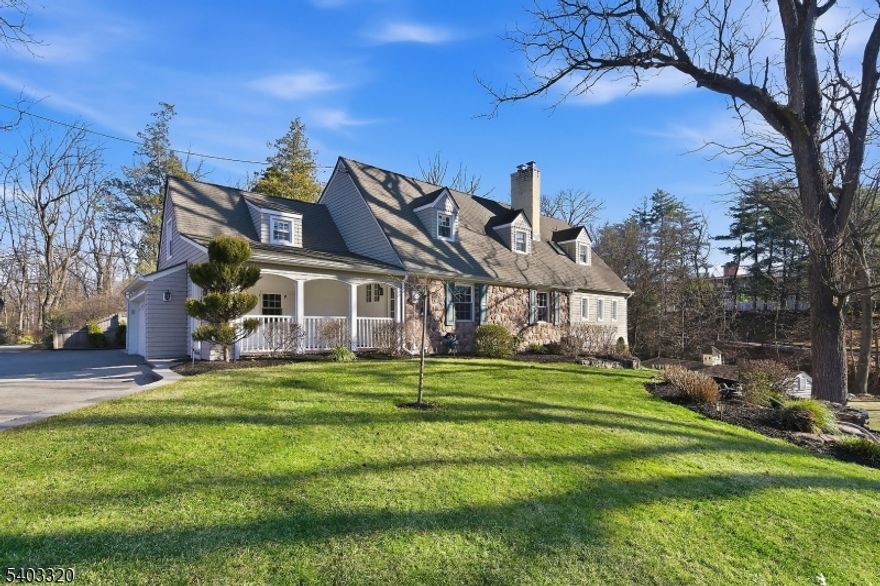 Perched on a hill along New Providence Road, this two-story ranch offers strong curb appeal, visibility, and a spacious property in desirable Mountainside. A covered front porch welcomes you home perfect for morning coffee or relaxing outdoors.Inside, the large living room features wood flooring, large windows for natural light, and a stone wall with a wood-burning fireplace. The adjacent kitchen is equipped with stainless steel appliances including a Wolf gas range with hood fan, granite countertops, pantry storage, and a separate dining area. A formal dining room with wood flooring sits just off the kitchen and living room, ideal for entertaining.The dining room opens to a spacious family room with a second wood-burning fireplace, wet bar, full bathroom, and sliders leading to a private patio and deck. All five bedrooms are located on the second floor. The primary suite features a walk-in cedar closet and full bath with shower stall. One adjoining bedroom is currently used as additional closet space and can easily be restored. The remaining four bedrooms are generously sized and share a full hallway bath.The finished basement provides flexible space for recreation, office, or gym, along with a laundry room and half bath. Exterior highlights include a private side yard, storage shed, attached two-car garage, and paver parking near the garage for additional off-street parking. Conveniently located near downtown Westfield, NYC train access, and nearby parks and trails.