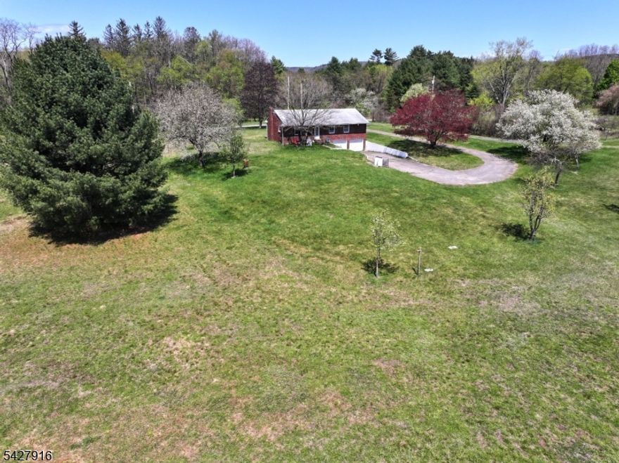 Set against the natural beauty of the Delaware Valley, this exceptional property offers over 83 farm-assessed acres directly across from the scenic Delaware River? rare opportunity to own a versatile slice of countryside w/ endless potential. Classic brick ranch home is designed for easy, one-floor living, featuring 3 spacious BR & 2 full baths. Hardwood floors run throughout living room, foyer & all bedrooms, adding warmth & timeless appeal. Inviting living room is anchored by a wood-burning fireplace, perfect for cozy evenings, while the eat-in kitchen includes a convenient pantry for everyday functionality Downstairs, a full unfinished basement expands your possibilities, complete w/ a 2nd full bath & direct access to oversized 2-car garage w/ automatic opener. Outside, ample parking accommodates up to 12 vehicles w/ ease. Land itself is the true highlight?over 83 acres of farm-assessed property ideal for hunting, horseback riding, dirt biking, or agricultural use. Charming apple orchard adds character & potential for hobby farming or personal enjoyment. Located just minutes from outdoor & recreational destinations like Milford Beach, iconic Appalachian Trail, Stokes State Forest, historic Walpack Valley, & Skylands Stadium, this property blends rural privacy w/ convenient access to recreation & entertainment. Whether you're seeking a private retreat, working farm, or outdoor enthusiast?s dream, this unique offering invites you to truly play where you live.