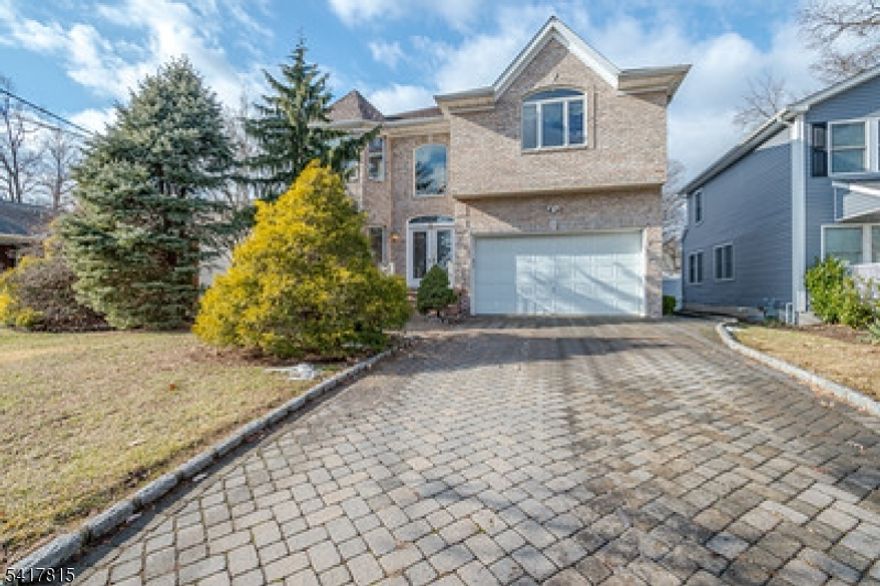 East-facing colonial home featuring a classic brick front, paver driveway, and inviting walkway leading to a bright, open foyer with a stunning chandelier and abundant natural light. The main level offers 10-ft ceilings, a spacious LR and DR combo with HW flooring, accented by elegant columns that define each space with timeless appeal and enhanced by a built-in surround sound system. The gourmet kitchen features SS appliances, a center island with seating, a mini bar/butler pantry. Custom windows on the first floor enhance natural light throughout. Sliding doors open to a fully fenced backyard with a paver patio and lawn, perfect for outdoor enjoyment. The family room offers HW flr, classic columns, a step-down design adding architectural character, and a conveniently located powder room. The first floor hallway connects to the laundry and pantry area and provides direct access to a two-car garage. The second level overlooks the foyer and offers a spacious primary bedroom with 8+ foot ceilings and a luxurious en-suite bath featuring a stall shower, jacuzzi tub, and two closets. Three bedrooms feature large windows and ample closet space. A full hall bathroom includes a tub and a double vanity. The unfinished basement has nine-foot ceilings, offering excellent potential for future customization. The whole house has central vacuum. Ideally located near the GSP, NJT, 287 & 1, shopping, dining, and Metropark Train Station.