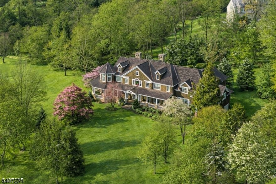 This Mark-built Hampton-inspired residence reflects timeless architecture and exceptional craftsmanship, introduced by a classic covered porch and a dramatic 20-foot foyer. Inside, 10-foot ceilings, oak floors, tall solid doors, and extensive architectural detailing define the home, including layered crown moldings, substantial base moldings, pilasters, built-up headers, and wainscoting throughout.The formal living and family rooms are distinguished by tray ceilings, fireplaces, expansive windows, and rich millwork, creating an atmosphere of warmth, scale, and classic sophistication. Generously scaled gathering spaces, a private office/library, and a first-floor en suite bedroom provide flexibility for guests or work-from-home needs.The upper level offers five bedrooms, including three en suite bedrooms among them the serene primary suite with sitting area, fireplace, and picturesque views overlooking the pond along with the convenience of a second-level laundry. Additional highlights include a generator, four-car garage, refined mechanical systems, and a setting enhanced by a scenic pond offering year-round enjoyment.Ideally located just minutes from the heart of Basking Ridge, with convenient access to Manhattan, local shopping and dining, and Ridge High School, consistently recognized among the nation's top public high schools.