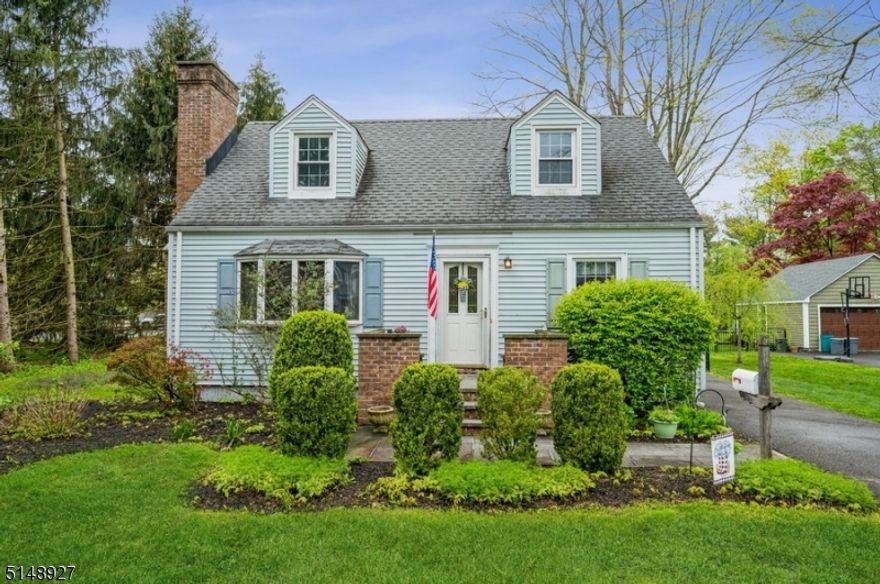 Quality home in a stellar location!  Spacious Cape Cod offers 3 bedrooms,1 1/2 bathrooms, a detached oversize 2-car garage, and a deck and patio in the private back yard. This home is tucked into the end of a dead-end road close to shops, restaurants, schools, and just half a mile to NJ Direct Train to NYC.  Highlights include an updated kitchen, hardwood floors, natural wood trim work, a fireplace, a deck topped by a pergola, and a stone paver patio with a built-in fire pit.  From the living room with a bow window and floor-to-ceiling brick surround fireplace, step into the open kitchen and dining area. The kitchen is updated with stainless steel appliances, warm wood cabinetry with crown molding, and granite countertops with a breakfast bar. A large, sunny family room and a dining area/den look out onto the deck and fenced-in back yard. A first floor bedroom and a full hall bathroom complete this level.  Upstairs are two spacious bedrooms, including the primary bedroom with an en suite half bathroom, plus attic storage. The full basement level offers a laundry area and extra storage.  To top it all off, the huge deck and fire pit on the patio are perfect for warm weather entertaining overlooking the lush, green back yard with plenty of space for gardening, playing, and relaxing.
