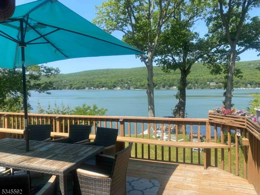 Waterfront residence on Greenwood Lake featuring 4 bedrooms and 2.5 baths with 50 feet of lake frontage and a private dock. This light-filled home offers vaulted ceilings, skylights, and an open kitchen and dining area with a wall of windows showcasing beautiful lake views and sliders leading to a spacious deck for relaxing or entertaining. The main level includes two bedrooms and a full bath with laundry, while the second floor offers the primary bedroom, an additional bedroom/bonus room, and a powder room. The walkout lower level features a rec room with wet bar, full bath with walk-in shower, and access to the patio and backyard, plus an 8-person hot tub to enjoy year-round. Conveniently located near the NY border and close to skiing, wineries, orchards, and Warwick, NY. 3-bedroom town verified septic.