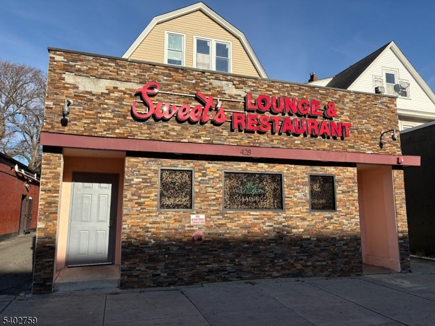 Welcome to this turn-key lounge and bar located in the heart of East Orange. This highly visible commercial property offers approximately 7500 square feet and can comfortably seat 100 patrons. The interior of the building was completely remodeled in 2015, providing a modern and inviting atmosphere. The sale includes a Plenary Retail Consumption (C) liquor license, adding significant value and opportunity for a new owner. The first floor features a beautifully remodeled bar with ample seating, surrounded by multiple TVs perfect for entertainment and events. A commercial kitchen equipped with the necessary equipment allows for food service operations and additional revenue potential. The second level offers tables and chairs set up for dining, while the rear bar area has been fully remodeled and includes DJ speakers above the bar and a dedicated loft-style DJ booth, along with additional seating. The property also includes two residential apartments: one four-bedroom, one-bath unit and one two-bedroom, one-bath unit. A full basement offers abundant storage space. This is a unique opportunity to own a versatile property with endless possibilities. Bring your vision and take this lounge to the next level. Walking distance to the East Orange Train Station with an approximate 25-minute commute to New York City, making this an ideal location for both business and residential use.
