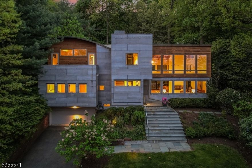 Perched on Montclair's First Mountain, this architecturally striking retreat is a rare fusion of modern luxury and natural serenity. Designed to inspire, the home's dramatic aesthetic features 25-foot soaring ceilings, exposed wood beams, walls of glass, and industrial-chic galvanized steel accents, creating a bold yet harmonious living environment. The sleek and flawlessly integrated chef's kitchen flows effortlessly into expansive living and dining areas, anchored by a stunning two-sided wood-burning fireplace. Oversized sliding glass doors blur the line between indoor and outdoor living, inviting you to entertain or unwind in the outdoor jacuzzi or the elegant patio surrounded by lush terraced gardens. Upstairs, a floating catwalk leads to an office that feels like you're in a treehouse, and a private primary suite sanctuary with a wood-burning fireplace, walk-in custom closets, and a secluded terrace. Indulge in the spa-like bath, featuring a deep soaking tub, oversized shower, and direct access to a tranquil balcony with sweeping views of the lush surroundings. Cap it all off with a rooftop terrace, offering front-row seats to dazzling sunsets and stunning NYC skyline views. This one-of-a-kind passive solar residence is as functional as it is beautiful. It boasts a three-story hydraulic elevator, cedar and Viroc exterior, radiant heat flooring, energy-efficient windows, a whole-house Sonos sound system, and underground irrigation. A truly magical place to call home.