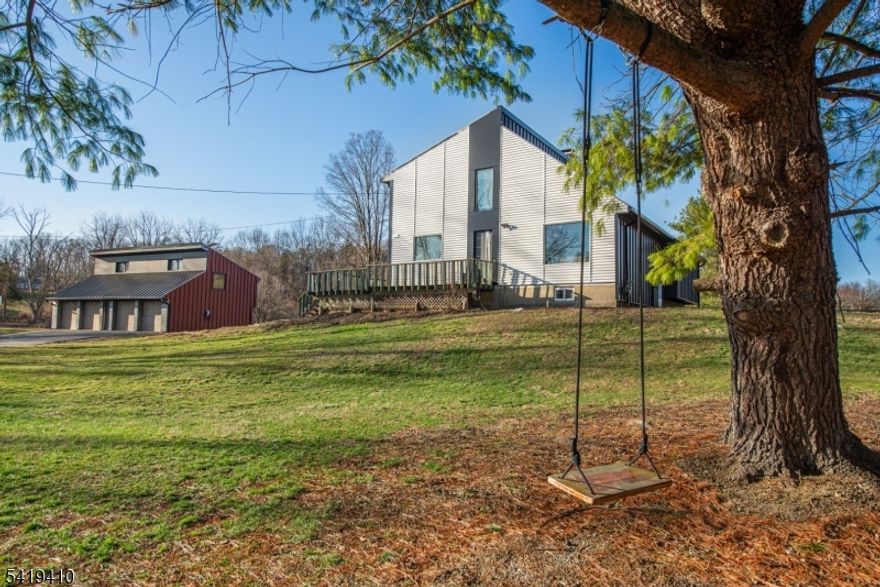 Welcome to a stunning custom home that's been completely transformed from top to bottom! New metal roofing & siding on this stylish 4 BR, 2 1/2 bath home as well as on the DETACHED 4-CAR GARAGE with 550 sq. ft. 2nd floor - IDEAL FOR CONTRACTORS-HOME OFFICE-STUDIO-HAS HEAT, AC,ELECTRIC!  This meticulously renovated home is set on a level 4.64 acre lot in an idyllic setting.  Gorgeous kitchen w/stylish cabinets and countertops, huge center island, beautiful tile backsplash, and stainless steel appliances. Updated hardwood flooring throughout the first and second floors.  First floor primary suite with cathedral ceiling and luxurious en-suite bathroom with oversized shower featuring double shower heads, beautiful tilework; double sink vanity; heated towel rack.  This exceptional home has excellent natural lighting - large new windows have been installed throughout.  The second floor has three spacious bedrooms, all with ample closet space.  Magazine-worthy second floor bathroom was just redone.  The finished basement has brand-new porcelain flooring and ample space to entertain or play.  Tons of storage space and a Bilco door to the exterior. Wood burner as is. New light fixtures throughout; new hot water heater; Tesla solar panel system; Tesla charging station; new windows. This meticulously renovated home offers a wraparound Trex deck overlooking the bucolic surroundings.  Just minutes to Farmstead Golf Course, Kittatinny State Park, schools, shopping, and commuter routes!