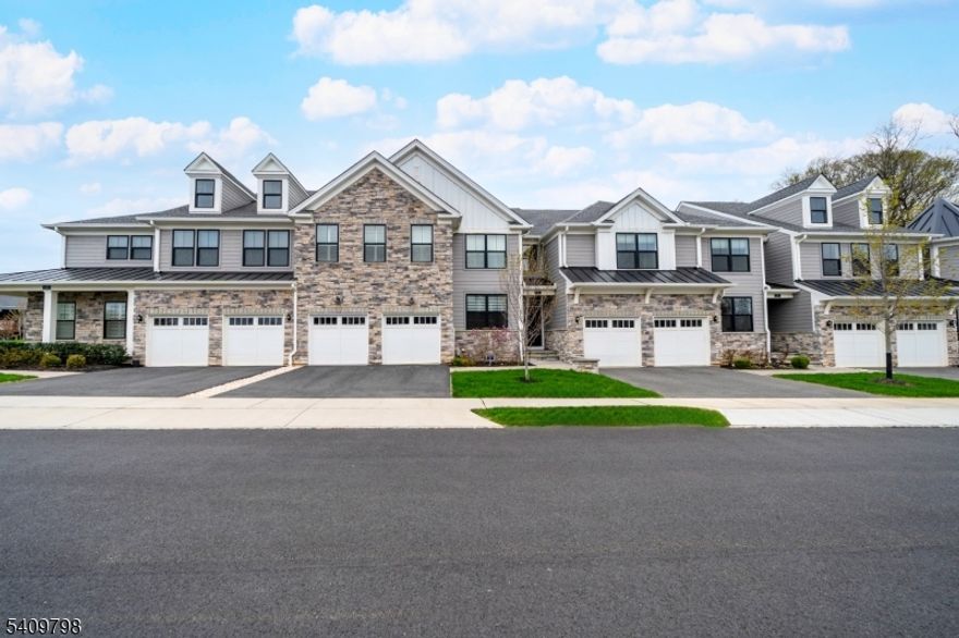 Refined townhome living meets exceptional convenience at the Villas at Warren, a sought-after carriage-style community in prestigious Warren Township. Located just 32 miles from New York City and within the highly rated Warren Township School District, this home offers the perfect balance of privacy, space, and accessibility. Inside, a bright open floor plan is highlighted by soaring ceilings, oversized windows, and wide-plank hardwood floors. The designer eat-in kitchen features JennAir appliances, custom black countertops, soft-close cabinetry, and an oversized center island ideal for gathering and entertaining. The family room is warmed by a gas fireplace and flows seamlessly into the dining area and out to a private Trex deck for effortless indoor-outdoor living. The main level showcases a spacious primary suite with a spa-like bath and walk-in closet, along with a home office or den, sitting room, powder room, and laundry. Upstairs, two additional bedrooms, a full bath, and a generous loft provide flexible living space. The finished lower level offers a second living area complete with a custom bar and performance stage perfect for entertaining or creative pursuits. Additional features include a two-car garage, two-zone HVAC, HardiePlank siding, and quality builder upgrades throughout. Enjoy the benefit of reduced taxes under New Jersey's PILOT program, all just minutes from downtown Warren, major highways, and NYC commuter options.