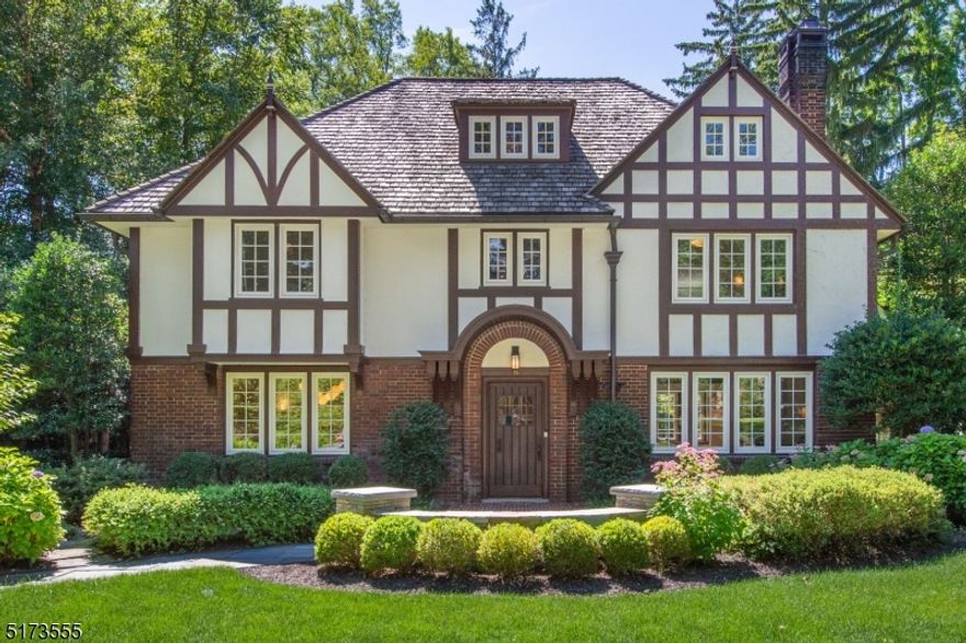 This radiant Colonial Tudor on a prime acre in Montclair's prestigious Estate Section is chock full of amenities, finishes, upgrades & flair. Its "simply wow" finished lower-level offers a media room, mirrored exercise studio w/steam shower, serious wine cellar, fridge/dishwasher/laundry, game space, pet station, extra powder room & separate entrance. The home's welcoming vestibule w/gold leaf ceiling opens into a stately foyer leading to gracious formal rooms. Beamed ceilings crown the freshly painted LR w/FP. Formal DR w/gorgeous original detail complements the exquisite Ulrich-designed kitchen w/granite counters, breakfast & wet bars, upscale appliances, dramatic closet lighting & turquoise Moroccan pantry inset. Also 1st Fl: charmingly re-created old-world-style PR, bright play/sunroom & amazing tucked-away den/office w/built-in bookcase & Fr doors to backyard. 2nd Fl: Landing w/pretty glass cabs; elegant primary suite w/white marble BA, dressing area w/built-in fl-to-ceiling closets, sitting room; 2 other ample bdrms, one w/en suite PR; updated hall BA, soaking tub. 3rd Fl: 2 bdrms; home office; elegant full BA! Home has multi-zone C/A & ceiling/floor Sonos sound; rich wood fls; all-new Andersen windows; low-maintenance copper gutters; cedar roof w/cool, multi-dimensional appearance; sprinkler sys; sec sys. Gracious bluestone patio & deep, wide property beckon to endless summer fun -- bring your own plans for a dream pool, cabana, tennis court, gardens. Splendid!