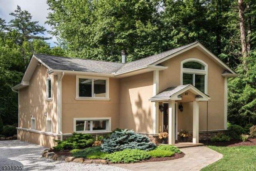 Live in your own private sanctuary! This updated home features a secluded, landscaped yard with an outdoor kitchen and stone patio for seamless indoor-outdoor living. The main level boasts a family room with a cathedral ceiling and a wood-burning fireplace, plus the primary suite and two bedrooms all with elegant wood flooring. A modern eat-in kitchen with a large island, stainless steel appliances, and a handy pantry, plus a dedicated dining room with a marble floor, are located on the ground floor. Enjoy a short 15-minute drive to Mountain Creek and other recreational activities. Outdoor storage and a shed.