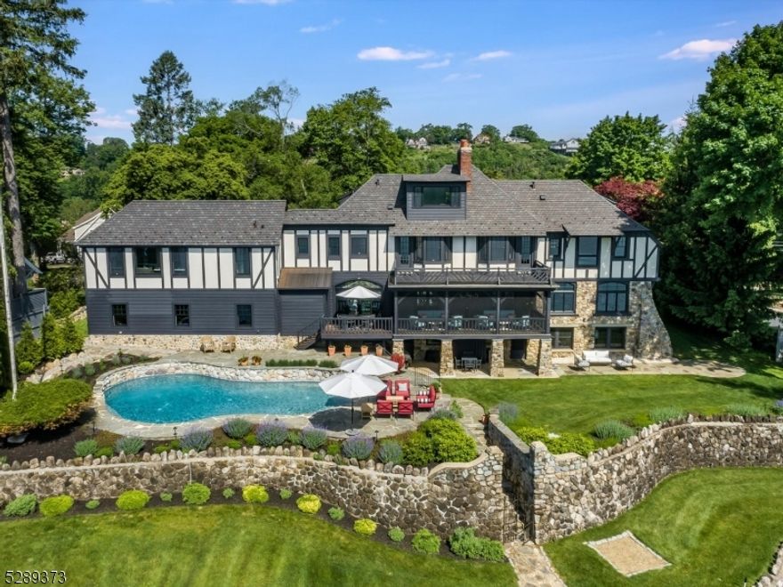 Truly remarkable Manitou Island Normandy Tudor cohesively melds modern luxury with the most charming and celebrated calling cards of the Arthur D. Crane company all while prominently positioned with a commanding panoramic view of Lake Mohawk. One of the earlier homes built on Lake Mohawk in the Crane style in 1932, this tastefully expanded home combines old world features like original rough hewn beams boldly framing the timeless two-story foyer and two tremendous stone fireplaces anchoring both the main living room and lower family rooms. Fully renovated kitchen highlighted by Subzero appliances and decadent quartzite slab countertops. Luxurious cararra marble countertops grace the bathrooms all w/ heated floors. Two potential primary suites plus an amazing attic office w/ a stellar view. The oversized back porch is usable well into the fall with a Bromic infrared heater and invisible screens which provide vast views of the largest open expanse of Lake Mohawk. The natural gas heated pool is newly resurfaced and tiled. Every window is brand new, juxtaposed against nearly 100 year old 'drunk brick', a technique of laying brick in an artful style on the facade that is rarely seen outside of Europe. Oversized 3 car garage w/ heat, A/C and water. New roof with snow guards and a heat to protect copper gutters.The built in dock provides ample space for multiple boats to enjoy water skiing, Fourth of July fireworks, or a sunset cruise to the Lake Mohawk boardwalk for ice cream.