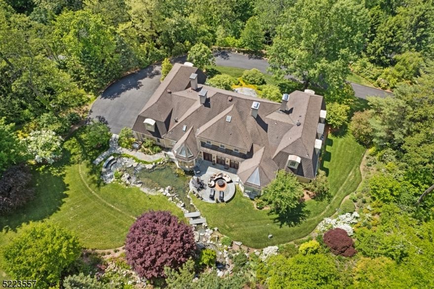 Enjoy awe inspiring views from every room of this captivating French Normandy design custom home boasting 7,770 sq ft of commodious living space on two sprawling floors and featuring a beautiful koi pond and the cascading water flowing from a picturesque man-made waterfall feature- a truly unique and architecturally dynamic home that blends striking design, dramatic proportion, and natural elements in the most compelling of ways.  Exclusively sited on 6.1 showcase acres in a private 5 home estate neighborhood accessible from a densely wooded private road with no outlet.  12 rooms including 4 airy bedrooms, 4 full baths and 2 powder rooms masterfully renovated using  the finest designer marble, onyx, and quartzite materials, 3 fireplaces, stately living room and formal dining room, gorgeous sunken great room has a wet bar and patio access, spacious gourmet designer kitchen with sun-filled dining area, and handsome library paneled in rich mahogany with French doors opening to a resplendent solarium.  Stunning 1st floor primary bedroom suite is in a private wing and provides the coveted option of one-floor living, and each large upstairs bedroom has a tasteful en suite full bath.  Four-car attached garage with custom  entranceway from a discreet meandering driveway.  Story book Mendham Borough location- rated #1 New Jersey town by NJ Monthly Magazine in 2013.  This elegant home is a true masterpiece