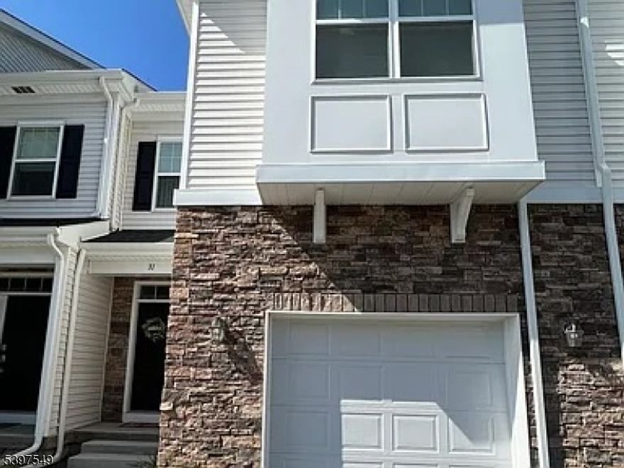 This beautiful move-in ready home is only 5 years old and offers over 2,400 sq. ft. of bright and modern living space. Featuring 9' ceilings on the first and second floors, an open-concept, and hardwood flooring, this home is designed for comfort and style. The upgraded kitchen has a large granite center island, high-end stainless steel appliances, a spacious pantry, recessed lighting, motorized blinds in the living room and master bedroom, and direct access to the deck for backyard grilling. A few steps from the garage lead you right into the main living area.The second floor offers a versatile loft space, a luxurious primary suite with two container store custom made walk-in closets, an office nook, and a spa-like bath with a double vanity and oversized stall shower. Two additional spacious bedrooms, a full guest bath, and a conveniently located laundry room complete this level.The fully finished daylight basement features high ceilings, an egress window, a family room with plush carpeting, a full bath, and ample storage. Additional highlights include a cozy gas fireplace in the living room, recessed lighting throughout, and efficient gas heat and central air. Situated in a prime location, this home is just minutes from major highways, two NJ Transit train stations, and the shopping and dining hubs of Morristown and Morris Plains. Tenant responsible for the first $300 in repairs.