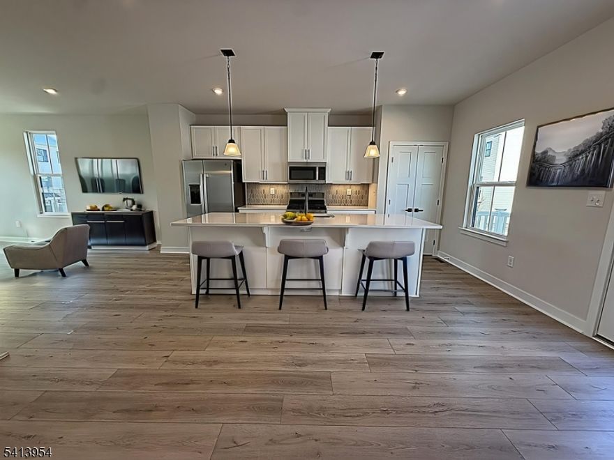 Step into this immaculate, never-lived-in new construction home offering modern design, flexible living space, and an unbeatable Hackettstown location near NJ Transit and downtown.The ground level welcomes you with a versatile flex room ideal for a home office, gym, or guest space plus a powder room and direct access to the 2-car garage, adding everyday convenience and extra storage.The main living level features an open-concept layout designed for today's lifestyle. The stunning designer kitchen includes quartz countertops, tiled backsplash, stainless steel appliances, and a breakfast island with seating perfect for entertaining or casual meals. Luxury vinyl plank flooring, recessed lighting, and seamless flow into the dining and living areas create a bright, modern feel. Step outside to your private balcony for morning coffee or evening relaxation. An additional powder room completes this level.Upstairs, you'll find 3 bedrooms and convenient second-floor laundry space. The primary suite is a true retreat, featuring a tray ceiling, walk-in closet, and a spa-inspired bathroom with double vanity and oversized walk-in shower. A full hall bath with tub/shower serves the additional bedrooms.Located in Hackettstown Crossing, just steps from downtown Hackettstown's restaurants, shops, and train station, this home is ideal for commuters. M&M Mars is approximately one mile away, making this a prime location for both work and lifestyle.