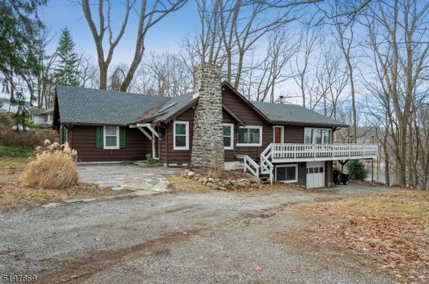 Welcome to lake life!  Expanded Arthur Crane original home is nestled on a half-acre wooded, private lot with seasonal lake views and sunsets. With three bedrooms, two full bathrooms, an attached one-car garage, and a wrap-around deck, this home exudes rustic charm and warmth with real wood paneling, cathedral ceilings, wood beams, parquet wood floors, and a massive fieldstone fireplace. The generous dining room offers ample space for entertaining as you dine by the fireplace with a skylight overhead bringing in plenty of natural light. The open flow continues to the kitchen, a cozy sitting room alcove, and an expansive living/family room with skylights and a wall of windows looking out on the deck and treetops beyond. A large grill and prep area on the deck makes outdoor cooking and dining easy as you enjoy the evening breezes and seasonal views of the lake. Two bedrooms, a den/office, and a full bathroom complete the main level. The refinished lower level includes the large primary bedroom, a full bathroom with a sauna, a spacious utility/storage area with a washer and dryer, and access to the attached garage. Thanks to this property's location in the Lake Mohawk Reservation, this home includes access to a beach, country club, boat docks, and endless activities all year long. Welcome to the lake lifestyle!