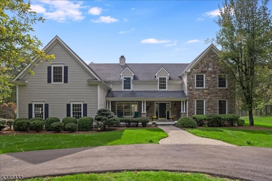 Privately sited on a quiet cul-de-sac, this striking stone and cedar residence, complemented by a three-car garage, is gracefully set on 5+ acres of manicured grounds surrounded by conservation land for lasting privacy. From the circular drive, the property unfolds to a backyard paradise with a saltwater pool, Tennessee sandstone patios, and deer fencing that preserves the landscaping's beauty. Inside, a two-story foyer opens to the formal dining and living rooms, enhanced by French doors and custom millwork. The expansive kitchen, breakfast room, and family room form the heart of the home, where walls of windows and a soaring fieldstone fireplace create warmth and connection to the outdoors. A mudroom with laundry, informal powder room, and back staircase ensure convenience. Upstairs, the primary suite offers a sitting area with gas fireplace, dual walk-in closets, and a spa-like bath. Two bedrooms share a Jack-and-Jill bath, with two more bedrooms and another full bath completing the level. The versatile lower level provides recreation space, a wine closet, half bath, storage, and direct walk-out access to the backyard. Backing to the 160-acre MacGregor Preserve with access to Chester's thousands of acres of parkland, hiking trails, equestrian facilities, and sports clubs, this location blends rural tranquility with commuter convenience, just minutes from farm stands, shopping, dining, award-winning schools, and Midtown Direct trains.