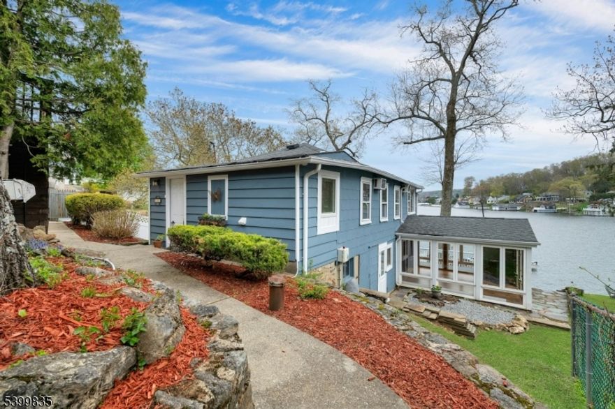 Enjoy year-round lake life in this charming lakefront home on Lake Hopatcong, New Jersey's largest man-made lake where motorboats are allowed. Offering 3 bedrooms, 1.5 baths, and parking for up to six cars.This property blends convenience and unbeatable recreation including - boating, fishing, ice skating, and much more. Located just minutes from major roads, restaurants, hiking, skiing and NJ Transit trains. The ground level features the kitchen, a half bath, dining/ family room, a sun room, warmed by a pellet stove; complemented by electric heat. Upstairs are three bedrooms, one with stunning lake views,one with a vaulted ceiling, ceiling fans, and wall air conditioners. An updated full bathroom with a modern walk-in shower.and a stackable washer/dryer complete the first floor. Outdoor living shines with a spacious deck, stone pavers, fully fenced yard and a firepit area ideal for entertaining. Additional highlights include a state of -the- art updated 3 bedroom septic system and optional membership to Elba Point Beach Club, which offers a private beach, club house,  boat/watercraft slip rentals, picnic area and more. Recent updates include: New flooring, some windows and fencing were replaced, freshly painted, newer water heater & well pump and the deck was refinished. There is a hook up for a generator for peace of mind! Don't miss your chance to own this lakefront property with year-round fun and breathtaking views. It's more than a home, it's a lifestyle!.