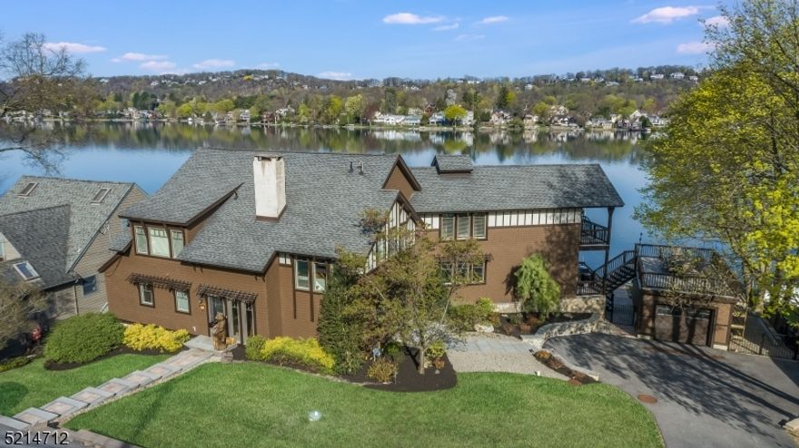 Experience lakefront living at its best in this exquisite 5-bedroom, 3 1/2-bathroom home that offers breathtaking views of Lake Mohawk from nearly every room. Situated on the convenient and highly coveted East Shore Trail, this property features a beautiful level lot with 130 feet of private shoreline.The open-concept living room and dining room provide a perfect space for entertaining guests, and the original Crane fieldstone fireplace and beamed ceilings add charm and character to the living room. The renovated designer kitchen boasts stainless steel appliances, granite countertops, and a center island with seating. Additionally, there are two bedrooms on the main floor that can be utilized as guest rooms or even as an in-law suite. On the second floor, the master suite is spacious and features a large private deck that overlooks the water. There is a full bathroom with a tub, stall shower, and double vanities.  In addition there are two additional guest bedrooms on this floor. Walk out fully finished basement, and very private outdoor space, hardwood deck and dock, make this so very perfect for entertaining. Natural gas hook up and so many upgrades. Located in the prestigious Lake Mohawk community, residents have access to a range of amenities such as beaches, a country club, golf course, tennis courts, and more. Don't miss out on the opportunity to own a piece of lakefront paradise in one of New Jersey's most sought-after communities.