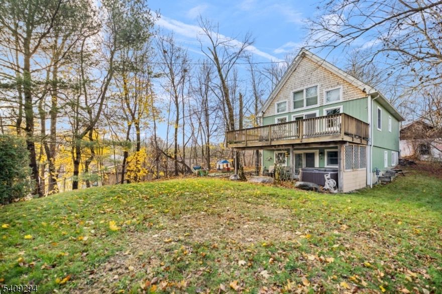 Step into this beautiful, custom timber-frame Cape set on a private road and located within steps of Greenwood Lake, offering privacy, craftsmanship, and a true lake-lifestyle setting. Completely renovated in 2019, this home features exposed post-and-beam construction, vaulted ceilings, and a bright, open living area that highlights the beauty of true timber framing. The home offers two bedrooms, each with its own en-suite full bathroom and walk-in closet, providing comfort and privacy. An open loft-style den overlooks the main living space and offers flexible use as a home office, guest area, or additional lounge space. Outdoor living includes a main-level deck and a lower-level patio, ideal for entertaining or relaxing in a peaceful setting. A detached garage provides space for additional storage along. Thoughtfully updated and just steps from the lake, this unique property delivers the feel of a private retreat while remaining suitable for year-round living!