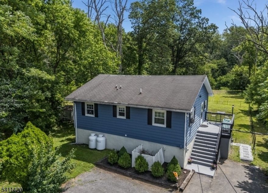 Renovated 3BR, 2BA expanded ranch on nearly an acre offering privacy, flexibility, and convenience with potential for an in-law suite. Set on a deep, tree-lined lot with seasonal views of the Musconetcong River, this home provides peaceful surroundings just minutes from schools, shopping, and commuter routes. Hardwood floors flow through the open-concept main level, highlighted by a stunning kitchen with granite countertops, stainless steel appliances, oversized center island, and walk-in pantry with a custom coffee station. Finished walkout basement includes a full bath and flexible space ideal for a family room, office, gym, or guest suite. Outdoor living features expansive decks, a private patio, a built-in fire pit, and generous yard space. Parking for 4+ vehicles. A berm was installed following a prior hurricane-related claim; since installation, there has been no water intrusion. Passing Septic (2021) and Passing Well Water Test (2025). From lush summer greenery to peaceful winter views, this home offers beauty in every season. Seller open to reasonable concessions (assist or rate buydown considered with strong offers). Possible USDA 0% down financing (buyer to confirm eligibility). Showings Saturdays & Sundays only.