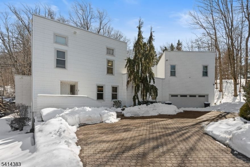 Expansive contemporary residence situated on a serene, wooded lot offering exceptional space, natural light, and a tranquil setting. Designed for both everyday living and entertaining, the open floor plan showcases hardwood floors, soaring ceilings, and expansive windows that flood the space with natural light while framing serene views. The main level features a spacious living room with fireplace and custom built-ins, seamlessly connected to the rear deck overlooking an in-ground pool, for effortless indoor-outdoor living. The bright kitchen is appointed with white cabinetry, and ample counter space, opening to the dining area for easy gatherings. The primary suite serves as a private retreat, complete with a marble bath featuring a soaking tub, oversized glass shower, and walk-in closet. Additional bedrooms are well-proportioned and supported by multiple full baths throughout. The lower level offers flexible living space ideal for recreation, fitness, studio, or media use, along with an indoor spa area featuring a soaking tub. A striking spiral staircase enhances the home's architectural character while connecting the living spaces with style. Additional highlights include skylights, abundant storage, a two-car garage, and private outdoor areas ideal for entertaining. Conveniently located near major highways, schools, and shopping. Available immediately