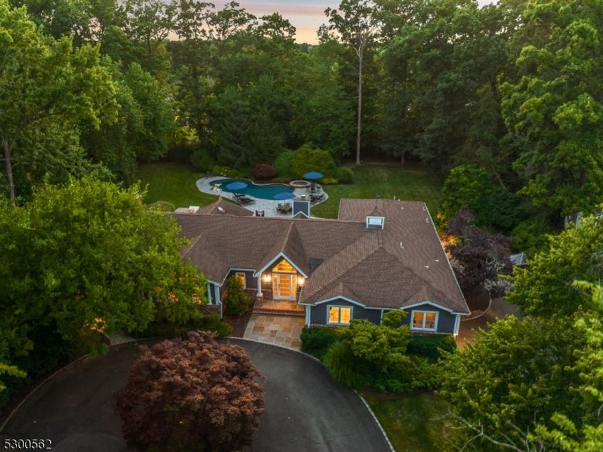 Nestled in Livingston's prestigious Coventry neighborhood, this expansive fully renovated ranch defines luxury and comfort. The Great Room exudes sophistication with coffered ceilings, a gas fireplace with stone surround, and French doors leading to a spacious deck. Striking wall textures and designer finishes enhance the room's elegance. The family room with its wood-burning fireplace and abundant sunlight serves as a cozy gathering space. The kitchen seamlessly flows into dining and leisure areas, showcasing state-of-the-art appliances, including a Viking range, a Wi-Fi-enabled double oven, Sub-Zero refrigerator and freezer, 2 Miele dishwashers, and automated sink faucets. The primary suite offers views of the property, complemented by bold wall coverings and lofty ceilings. The en-suite bath includes sleek fixtures and a spacious shower, while the walk-in closet, designed like a boutique, has custom shelving and a center island. The sunlit lower level boasts high ceilings, shiplap walls, and versatile space for recreation and entertaining, including a custom wet bar. A 5th bedroom with an en-suite bath, a powder room, and access to the 2-car garage complete this level. Expansive Trex decking offers an ideal setting for outdoor living with a built-in kitchen complete with a gas grill, refrigerator, and sink. The pool area includes a Pugliese heated pool and spa, surrounded by lush landscaping and stone decking, with a built-in firepit completing this resort-like backyard.