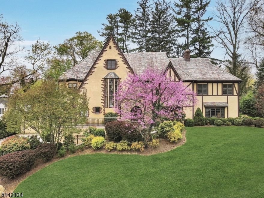 The beauty and enchantment of this luxurious Short Hills Tudor is indescribable! The architectural gem with slate roof, stunning stonework, striking peaks and paver drive has curb appeal galore and is truly a forever home. Set on .38 acres of lush landscaped grounds, this gracious residence enjoys a prime location near train, shopping, highways, top schools and more. Impeccably designed interiors present grand living-entertaining areas, 7 bedrooms and 4.2 baths. Tranquil outdoor spaces include a blissful bluestone patio with nearby wood-burning firepit for alfresco dining/entertaining and magnificent broad flat partially fenced yard for recreation. Unlike many Tudors, ample light streams in through generous oversized windows. The sophisticated, inviting main level greets you with an elegant reception hall and presents an expansive living room with wood-burning fireplace, wood beams and massive windows. Adjoining is a wainscoted dining room for hosting guests in style with French doors to the outdoor oasis. Plus a sun-filled family room with built-ins; new white chef's kitchen; divine primary suite with custom walk-in closet, 2-person office and spa bath; third floor with 3 bedrooms -- perfect for guests, offices or multipurpose; finished lower level with recreation and exercise rooms, laundry and 3-car garage. This magical house on a quiet street also has a standby generator. As alluring is the prime address near it all and a 5-minute stroll to top-rated Glenwood Elementary.