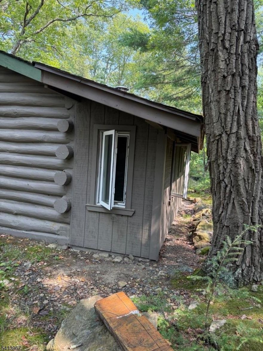 Nestled on top of the mountain in West Milford, this unique one-acre property offers privacy, character, and endless potential. A rustic cabin sits on the land, featuring a wood-burning cast iron stove, a bathroom with a septic system that is currently not compliant but usable, and a private well without running water. Electricity can be reinstated as it was once connected, but the lines were dropped from the telephone pole and never reinstated. The cabin has been used by the seller's family and friends as a cozy getaway, with temporary electric hooked up from the main house. There is also a 15x15 "deck in the trees,  a special spot the seller created to enjoy morning coffee and quiet moments surrounded by nature. The property is level where a home once stood, offering rare usability on top of the mountain, and provides seasonal views of Greenwood Lake in the winter. Beautiful hiking trails nearby make this an outdoor lover's dream. Accessed by a shared driveway with the neighboring cabin, this hidden gem offers a truly unique opportunity. West Milford is filled with special areas like this one, and this property is perfect for someone who appreciates the outdoors, rustic charm, and the vision to create something remarkable.