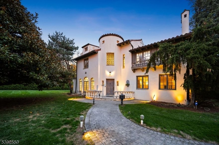 Welcome to 3 Serafin Place, a striking Spanish Revival luxury residence offering five bedrooms and four-and-a-half baths across nearly 4,500 square feet of refined living space, set on a beautifully landscaped half-acre in the heart of Glen Rock. A grand foyer with soaring ceilings and rich finishes creates a striking first impression, leading into a thoughtfully designed semi-open layout . Formal living and dining areas flow seamlessly into the gourmet kitchen, appointed with marble countertops, an expansive center island, and a sunlit breakfast nook overlooking the serene yard. A mudroom and powder room add everyday convenience, while the residential elevator provides seamless access to all levels. The upper level is highlighted by a lavish primary suite offering a private sitting area, fireplace, and spa-inspired bath. Two additional bedrooms, bright home office, and a full bath complete this floor. The third level offers an ideal guest or junior suite, lounge area, and full bath. The finished lower level extends the living space with a rec room, full bath, and laundry. Outdoors, the private fenced yard is a true retreat, featuring lush landscaping, pristinely maintained hedges, tasteful statues, and a luxury patio, perfect for entertaining or quiet relaxation. Enhanced with smart-home technology, including multi-zone climate control, lighting, and irrigation systems. Ideally located near downtown Glen Rock, top-rated schools, and direct NYC transportation.