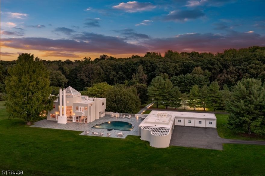 A sophisticated modern design by the noted architectural firm of Gwathmey Siegel provides exceptional facilities for an active resort lifestyle in one of the beautifully peaceful and accessible sites in Harding Township just 35 miles from Manhattan. Generous interior space of over 13,000 sq ft is augmented by segmented sport-related facilities that include on a gymnasium level an indoor half-court sports court and adjacent 36x20 exercise room with sauna. An outdoor lighted tennis court and a pool complex with delightful guest quarters and 4-car garage are set a short distance away off a linking terrace. Interior space has a minimalist design yet provides ample entertaining areas. Accented by extensive built-ins the feel is sleek and clean, simple yet dramatic, lighted by windows with breath-taking views of the 15.82 ac farm-assessed grounds. A double-height glass rotunda at the heart of the home crowns the great room, dining and sitting rooms. The well-outfitted Kitchen includes a walk-in pantry and separate breakfast room. Completing the 1st floor is a wing with 2 ensuite bedrooms. A sprawling primary suite located on the 2nd floor with ensuite bathroom facilities; walk-in closet; a remarkable dressing room and library/office. Beyond the hallway laundry are 2 ensuite bedrooms and a kitchenette. The ground level provides access to the 40'x27' game room that overlooks the sports court; bedroom #6; a second laundry; mechanical and storage rooms; and access to the garage.