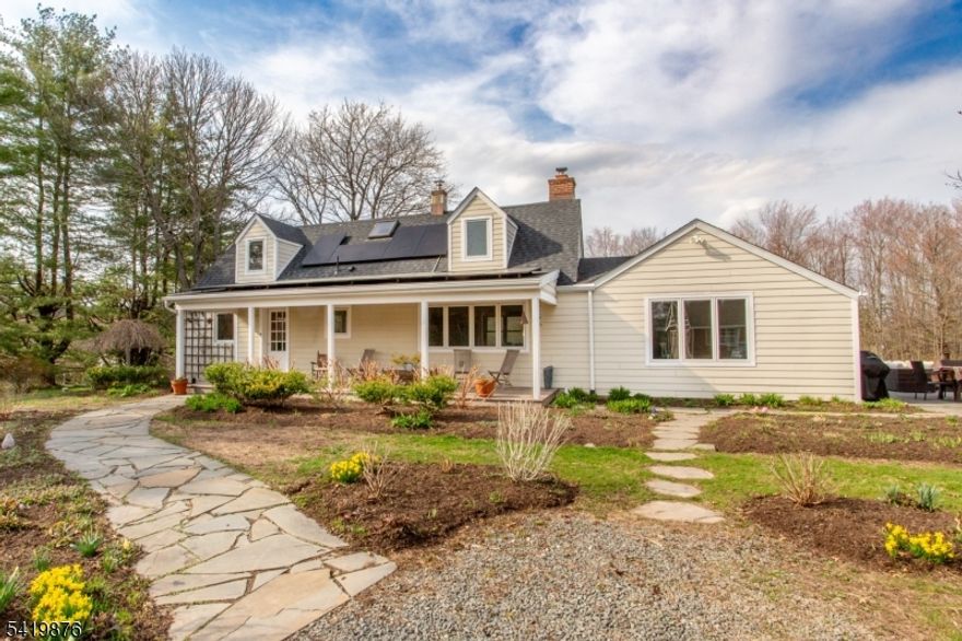 History and artistry merge with modern amenities in this thoughtfully expanded farmhouse. Set on over two acres, this peaceful retreat offers long-distance views, just minutes from Lambertville and Hopewell. A bluestone walkway winds through mature landscaping, leading to the rocking chair front porch. The inviting eat-in kitchen offers stainless steel appliances, granite countertops, and custom birch cabinetry. The dining room is filled with natural light and showcases original pine floors, and the cozy living room has a woodstove set within a white brick fireplace and custom built-in shelving to create a warm gathering space. Beyond is a great room with vaulted ceiling and sliding glass doors that open to a bluestone patio overlooking the backyard with raised garden beds and native specimen plantings. The first floor primary suite is a private retreat with patio access, generous closet space, and an ensuite bath with a two-person soaking tub and custom dry sauna. Upstairs, two bright bedrooms share a beautifully appointed hall bathroom. The basement provides clean, dry storage and laundry. Notable upgrades include; fully owned income-generating solar panels, an electric vehicle charging station, and abundant storage throughout. This unique property offers a rare blend of beauty, charm, and local artistry, all set on an expansive lot with picturesque views while remaining convenient to major commuting corridors and cultural hot spots of Philadelphia and NYC.
