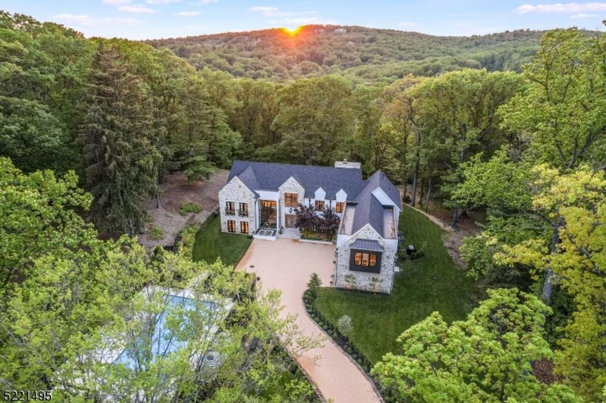 Newly built from the ground up in 2019, this residence is a dramatic example of romantic modernism nestled into its private 3 acre setting on Round Top Road, where it provides winter views of the Somerset Hills Country Club. Surrounded by serene natural beauty, this custom residence is finished in a nuanced mix of stone, stucco and HardiePlank.  Interior highlights include an open-concept floor plan filled with natural light from towering windows, 3 natural-gas fireplaces topped by custom-created mantles, 9 foot ceilings, all Pella French doors and windows, plus chic tile work and innovative lighting throughout. The sun-splashed entrance reveals an open staircase, soaring 20 foot ceilings with views, which also lend character to the adjacent living and dining rooms. A true chef's kitchen contains upper-end amenities a home cook desires, such as Miele appliances, 2 French Chambord sinks, unique cabinetry, an enormous center island, built-in barista center and dining area. A refined first-floor primary suite includes a see-through fireplace. A spa-like primary Bath is designed with an oversized steam shower, double-sink vanity, heated floor and bidet. Upstairs are 4 more en-suite bedrooms; one of the generous bedrooms, currently used as a office can alternatively become a secondary primary or family room. A laundry room is on this level. The outdoor living room provides a fireplace and is adjacent to the lavish butler's pantry. Pool renovated in 2022 and is edged by gardens