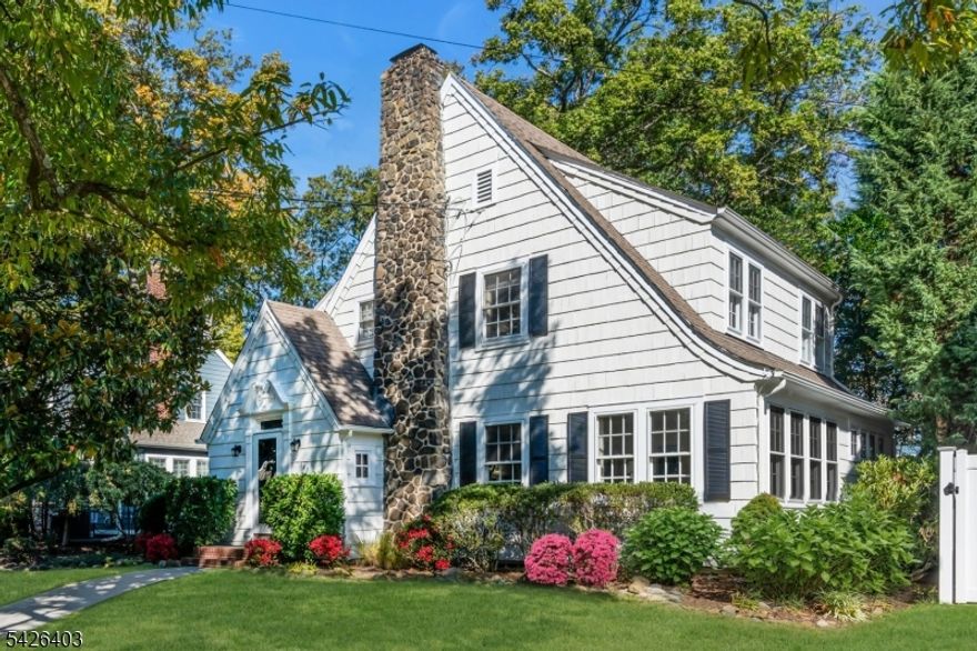 This classic 1929 Colonial blends timeless character with storybook charm and a warm, inviting feel throughout. Passing beneath the entryway's original millwork and leaded-glass transom window, you're welcomed into sun-filled spaces defined by high ceilings, a graceful arched opening, and an easy flow. The oversized living room is a standout, centered around a stately original stone fireplace and lined with windows that bring in beautiful light throughout the day. Just beyond, a tucked-away den sits behind French doors, offering the perfect private office or quiet retreat, with a bay window that adds charm and dimension, along with original casement windows overlooking the dining room. The dining room flows effortlessly into the kitchen and opens outside through French doors to a patio and deck, ideal for everyday living and entertaining. The eat-in kitchen features cherry-tone cabinetry, tall pantry cabinets with pull-out shelving, and space to gather. Upstairs, the primary bedroom is spacious, with two additional bedrooms that offer comfortable proportions. A walk-up attic adds a flexible bonus space for play, work, or creativity, plus separate storage. The finished basement provides additional room for recreation, laundry, and storage. Outside, mature landscaping, manicured lawns with irrigation, and a detached two-car garage complete the setting. A home with presence, character, and a layout that simply feels right, set in a wonderful neighborhood.