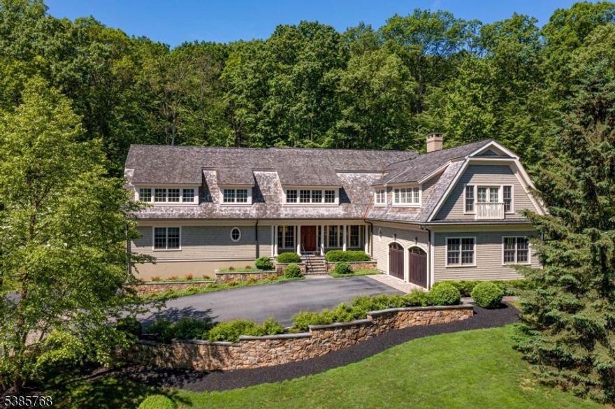 Stunning 2010 Shingle-style home designed by noted architect Nick Cusano with interior decoration by award-winning Katja van der Loo. Sited on a promontory on its almost 7 AC on the Bernardsville Mountain on a cul-de-sac street. Privacy, privacy!  Mature trees, flowering shrubbery, stone walls & a stream highlight the property. Step indoors from the bluestone floored front porch to a generous-sized entry foyer with handsome staircases, walk-in guest closet wide oak floor & custom lighting. Rooms are generously sized yet warmly inviting. The beamed great room ceiling is a work of art. Anchoring the room is a raised-hearth fieldstone floor-to-ceiling fireplace.. Circular windows flank the fireplace. Two sets of French doors provide access to the wrap-around ipe deck. French doors from the Entry Foyer open to the living room featuring French doors to the deck & 2 oval windows. The Bar is conveniently located between the living and great rooms and features a temperature-controlled wine room with slate floor. There is a first-floor office. A marble floor highlights the formal powder room. Wainscoting accents the Dining Room. The  Designer kitchen features a stone floor, high-end appliances, indoor barbecue & center island. The Den, mudroom & informal powder room complete this level.The luxurious primary suite is flooded with natural light & the white marble bathroom is spa like. A loft, 3 more bedrooms, 2 more baths & laundry complete the 2nd floor. Finished LL.(