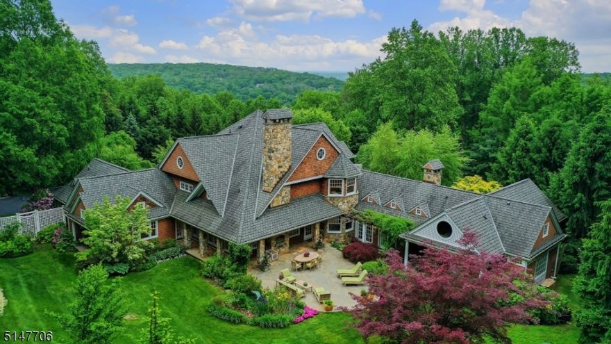 A one-of-a-kind architectural masterpiece specifically designed to be at peace with nature. Majestically nestled on over 1.3 private and tranquil mountaintop acres and elegantly framed by sprawling lush lawns and mature specimen plantings, this stunning cedar shake residence by renowned Hiland Hall Turner Architects is ideally situated at the end of a quiet cul-de-sac of distinctive and prominent estates. Awaiting visitors at the end of a long drive, this home creates a commanding presence and promises no less. A pair of 8' beveled mahogany glass entry doors welcome you into this timeless design, boasting 5 BRs, 5.1 BAs and a first-floor primary suite with luxurious spa-like bath that affords one floor living at its best. Having won landscaping design awards, the owners used their considerable expertise to create their own botanical oasis. In turn, the home was situated to offer breathtaking views from every room, many with balconies, bringing the picturesque outdoors in. The Aspen-inspired family room boasts barnwood floors, vaulted pine ceilings, massive beams and a floor-to-ceiling 16' stone fireplace, while the nearby chef's kitchen was designed to be the heart of the home. This residence is substantial, with 6,720 sq ft including a finished walk-out basement, offering flexible spaces for multiple home offices and multi-generational living. Plenty of room for a pool. Convenient access to NYC (29 miles), 15 min to Summit train, shopping & public & private schools (Pingry).