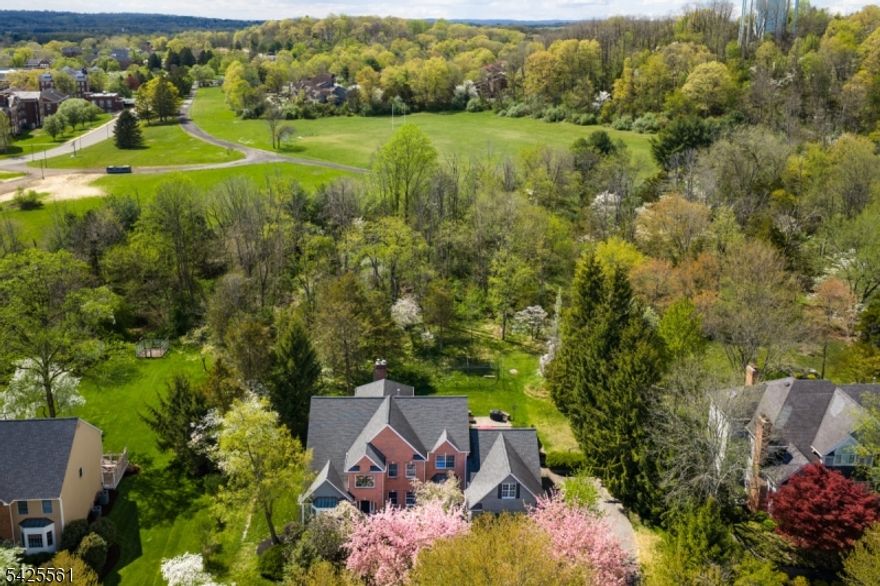 Sun-filled and east-facing, this distinguished brick and clapboard Colonial with hardwood flooring on first and second level, sits on a level .69-acre lot in a private, serene setting in the desirable Sherbrooke neighborhood. This four bedroom, two-and-a-half bath home offers 4,575 square feet of thoughtfully designed living space. A dramatic two-story foyer opens to a soaring two-story family room anchored by a floor-to-ceiling brick fireplace, filling the home with natural light throughout the day. Privacy and ease define the rare first-floor primary suite, a feature discerning buyers actively seek. The ensuite bath includes a custom-built sauna. The kitchen offers generous counter space, a center island, and flows naturally between formal and informal areas, equally suited to quiet mornings and large gatherings. Completing the main level are a formal living room, dining room, private office, mudroom, and first-floor laundry. Upstairs, three well-proportioned bedrooms share a full bath. A versatile bonus room with its own dedicated staircase to the first floor adapts readily as a fifth bedroom, playroom, or private workspace. The home's systems include newer furnaces and one newer AC unit (2021). Generous and level, the property offers valued space for outdoor living and recreation. A home of this scale, configuration, and condition rarely comes to market. All this, close to major transportation and within the nationally ranked Basking Ridge school system.