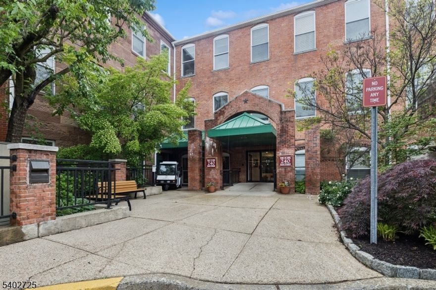 This stunning two-bedroom corner residence occupies a top-floor position within the 240 building and offers a bright open layout with abundant natural light! Wide-plank flooring and high ceilings create an airy feel throughout the living spaces. The living room is generously sized and anchored by a wood-burning fireplace creating a strong focal point for both everyday living and entertaining. A mirrored accent wall enhances the sense of scale and reflects natural light across the space. The open layout flows comfortably into the dining area, highlighted by a contemporary chandelier. The kitchen features white cabinetry, granite countertops, a tile backsplash, and stainless steel appliances, offering a clean and functional workspace that connects easily to the main living area. The expansive primary bedroom offers seasonal views of the waterfall, a large walk-in closet with built-in shelving provides excellent storage and the bathroom includes a modern vanity and tub-shower combination. In-unit laundry adds everyday convenience! Neutral finishes throughout create a cohesive, move-in ready atmosphere. Residents of The Mill enjoy access to a fitness center, community room, in-ground swimming pool, tennis courts, walking and jogging paths, and the plaza deck overlooking the waterfalls, along with nearby shopping, dining, and convenient access to NYC transportation.