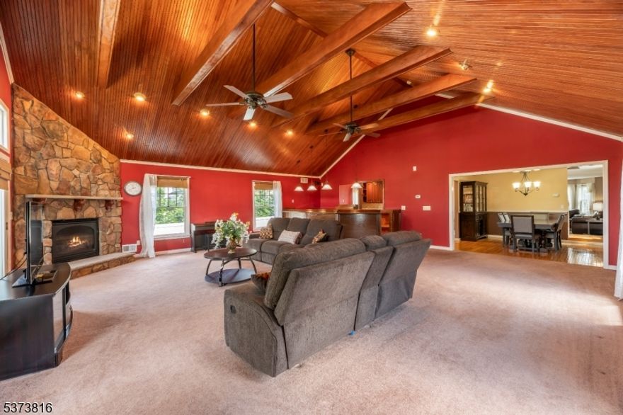 Welcome to this custom colonial! The great room is the heart of the home, featuring striking wood cathedral ceilings, large windows for abundant natural light, a gas fireplace, and an extended wet bar. The updated kitchen features cherry cabinets, quartz countertops, a range with double ovens, a vented microwave, and stainless steel appliances. A convenient pass-through window from the kitchen to the great room is perfect for entertaining and keeping the kitchen connected to the main living space. The living room offers bay windows and gleaming hardwood floors. Upstairs are three bedrooms, including a spacious primary suite with an oversized closet and en-suite bath. The second bedroom features bamboo hardwood flooring. Bathrooms include modern LED mirrors. The fenced-in expansive backyard offers a Trex landing and retractable awning and generous open space with privacy. Two doors from the great room provides access to the yard. The two-car-wide driveway offers plenty of parking. Dry large basement with sump pump allows for plenty of storage, plus a crawl space under the great room. Additional highlights include two-zone HVAC (zone 1 is just 1 year old) and a brand-new hot water heater. 3 mi to train station to NYC.