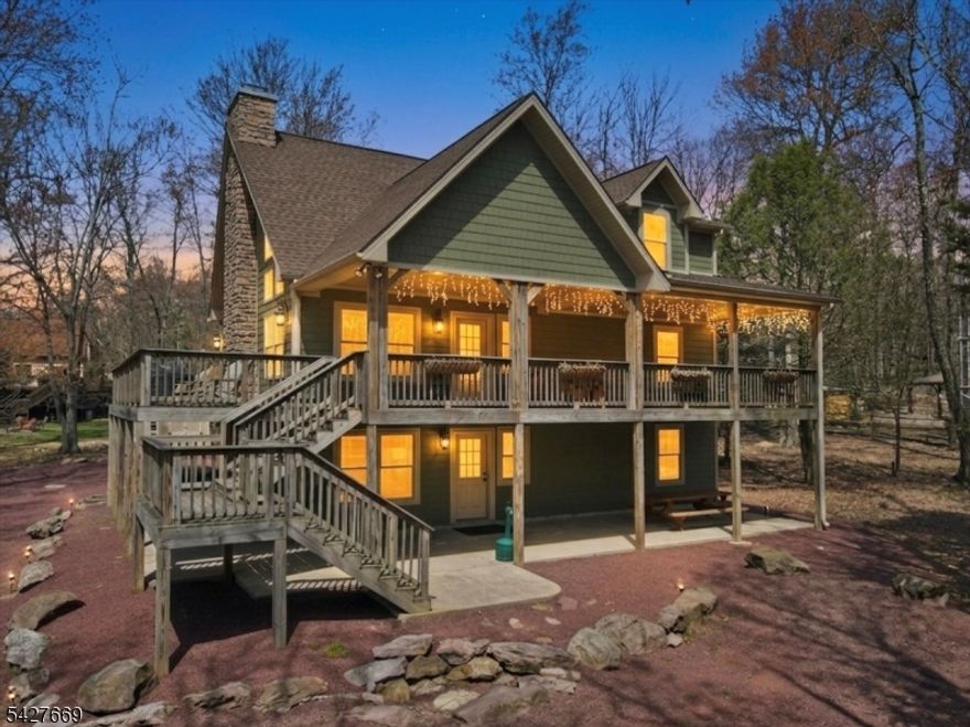 Set within Lake Harmony Estates, 12 Lupine Drive is designed around how people gather, connect, and experience time together in the Pocono Mountains. This three-level chalet balances scale, layout, and setting to function as both a private retreat and a destination for shared experiences.The main living level features vaulted ceilings, exposed beams, and a two-story wall of windows that fills the space with natural light. The open layout connects the living, dining, and kitchen areas into one cohesive environment, anchored by a double-sided stone fireplace that extends toward the outdoor deck.With six bedrooms, a loft, and three full bathrooms across three levels, the home supports both group living and private retreat. The lower level offers a recreation space with walk-out access, while the loft overlooks the main living area.Approximately 3,000 square feet of living space is complemented by extensive covered porches, patios, and decking, along with a hot tub area, exterior fireplace, and multiple outdoor seating zones.The flat lot includes a detached two-car garage and an extended driveway with substantial off-street parking. Located near Jack Frost Mountain and Big Boulder Mountain, with nearby golf and lake access, the property supports year-round use.Currently configured for short-term rental use with an established history; buyer to verify all use and regulations.