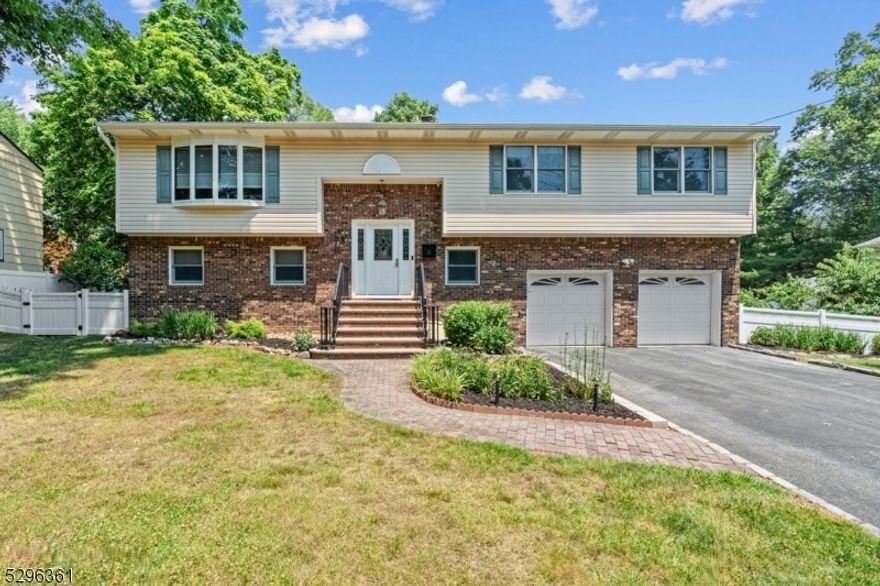 This expansive custom bi-level home, located on a tranquil street, features a two-car built-in garage and a spacious six-car driveway. The ground floor includes a large bedroom, a full bath, and a beautiful family room with a wood-burning fireplace. The upper floor offers a primary bedroom with an en-suite bathroom, three additional bedrooms. Step inside to discover an inviting open-concept floor plan where the center island flows seamlessly into the dining area and living room. Various lighting colors in the family room, living room, kitchen, and dining room create a relaxing atmosphere. The outdoor area is perfect for entertaining, featuring a large deck, a huge patio, and a garden backyard. A white vinyl fence provides privacy and elegance.
