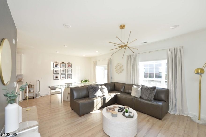 Welcome to this ultra-modern townhome located in the sought-after The Parke at Little Falls, freshly built just two years ago and offering a seamless blend of style, comfort, and convenience. This sun-drenched residence instantly welcomes you on the ground level with a stunning designer eat-in kitchen featuring pristine white cabinetry, sleek stainless steel appliances, and elegant finishes. The kitchen flows effortlessly into the open-concept dining and living areas, where expansive windows flood the space with natural light and provide direct access to a private patio, the perfect setting to relax or entertain. The first floor also offers a modern full bathroom, a dedicated laundry room, and convenient access to the private garage. Upstairs, the home continues to impress with a generous primary bedroom adorned with modern wallpaper, a tasteful chandelier, and a beautifully appointed en-suite bathroom. An additional spacious bedroom, equally stylish with modern finishes and chandelier lighting, is complemented by a full hallway bathroom. Ideally located just minutes from Willowbrook Mall, this home offers easy access to premier shopping, dining, Costco, coffee shops, bakeries, and effortless transportation options with a direct route into NYC. This move-in-ready townhome delivers modern luxury and everyday ease, one you won't want to hesitate to call home.