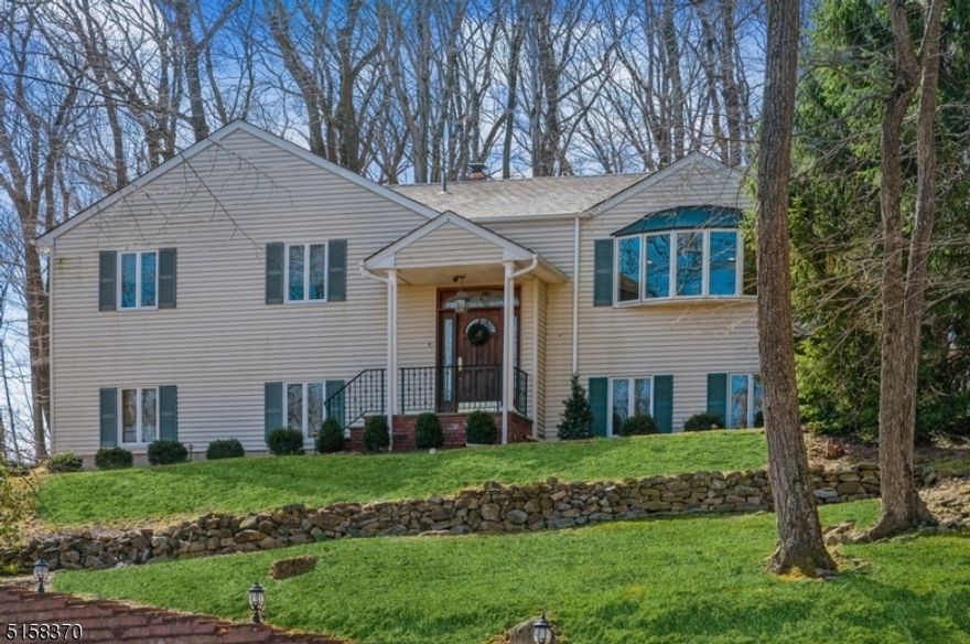 Stylish and spacious home in an unbeatable location! Beautifully updated and maintained Bi-Level home is situated on more than half an acre in the coveted Bradford Estates neighborhood of Morristown. This property is well located just minutes to downtown shops and eateries, nearby parks, schools within three miles, and a ten-minute drive to the Midtown Direct train station. Highlights include gleaming hardwood floors, recessed lighting, crown and picture frame moldings, a stunning custom kitchen, and a sprawling stone paver patio in the private back yard that is perfect for al fresco dining, entertaining, and relaxing. The main level of this sun-filled home includes an open living and dining room combination with two walls of windows letting in lots of natural light. Preparing meals is a delight in the large kitchen featuring gorgeous custom cabinetry, granite countertops, stainless steel appliances, and a bright breakfast nook. Throw open the sliding glass doors to enjoy the private, wooded scenery from the patio. Down the hall are three bedrooms, including the primary suite with a walk-in closet and full en suite bathroom, plus another full hallway bathroom.The lower level encompasses a large recreation room including a custom stone fireplace with a carved oak mantel and built-in cabinets, a fourth bedroom that could be used as an office, a half bathroom, laundry room, and an attached two-car garage.