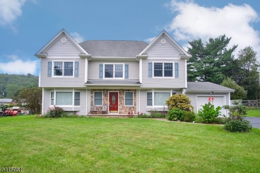 This beautifully expanded 5-bedroom Colonial offers space, flexibility, and comfortable living in a quiet neighborhood with a terrific level backyard. Originally renovated and expanded in 2005, the home features a versatile floor plan designed for modern lifestyles. The first floor includes an oversized living and family room area, a spacious kitchen and dining room ideal for everyday living or entertaining, and a convenient first-floor bedroom with a private bath suite that is perfect for guests. Upstairs you will find four additional bedrooms, including a generous primary suite with volume ceiling, private bath, and large walk-in closet. Oak hardwood floors run throughout much of the home and thoughtful upgrades add to the overall quality and comfort. Enjoy year-round climate control with three-zone heating and two-zone central air conditioning. The partially finished basement provides additional versatility with space for recreation, a workshop, and extra storage. Outside, the expansive level yard, large driveway, and attached garage offer plenty of room for outdoor enjoyment and everyday convenience. Ideally located just minutes from the Mount Arlington train station and major commuting routes including Rt 46, Rt 10, and Rt 80, this home combines suburban tranquility with excellent accessibility.