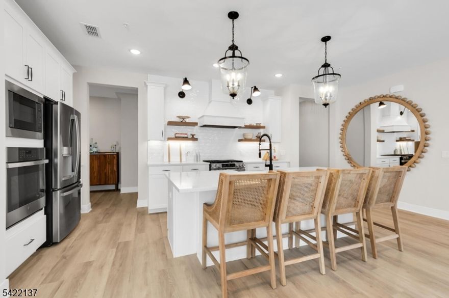 Discover refined, effortless living in this stunning 2-bedroom, 3-bath townhome in the desirable Hills at Warren community. Built in 2025 and professionally decorated, this sophisticated residence blends modern design with timeless appeal. Premium details abound, including wide plank LVT flooring, oversized baseboard moldings, designer tile work, and abundant storage solutions. The chef's kitchen is built to impress with sleek white cabinetry, quartz countertops, a GE stainless steel double oven, stainless steel vent hood, and a large center island perfect for gathering and entertaining.The open-concept floor plan is filled with natural light and flows seamlessly for everyday living and elegant entertaining. The electric fireplace adds to the Inviting ambiance. The spacious Primary bedroom features its own ensuite bath, with both the Primary and Second bath highlighted by striking black fixtures set against pristine white finishes. Sliding glass doors open to a private patio, offering effortless indoor-outdoor living and a peaceful space to relax. Ideally located near major highways, shopping, dining, and more, this turnkey home delivers the perfect balance of luxury, comfort, and convenience.