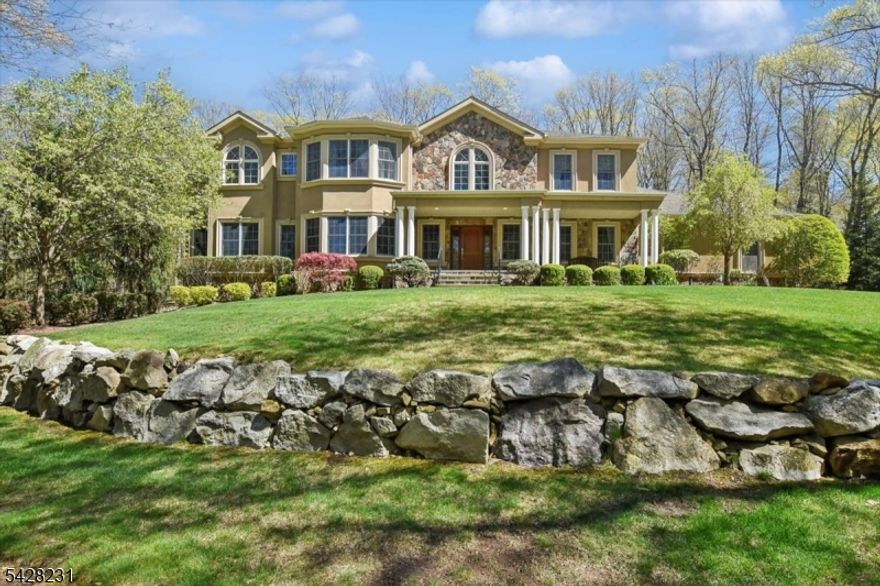 An elegant stone and stucco residence offering refined luxury and exceptional craftsmanship throughout. With soaring ceilings and premium Brazilian hardwood floors, this home was designed for both everyday living and entertaining. The gourmet kitchen is equipped with high-end Wolf appliances, granite countertops, soft-close cabinetry, and a substantial center island. A wet bar and wine cooler add to the home's entertaining appeal. Every bedroom is private, each featuring its own full en-suite bathroom and at least one walk-in closet. Additional highlights include two private first-floor offices with coffered ceilings, a spacious walk-up attic, and a three car garage. Set on a private lot with serene natural views, this home offers both privacy and sophistication.
